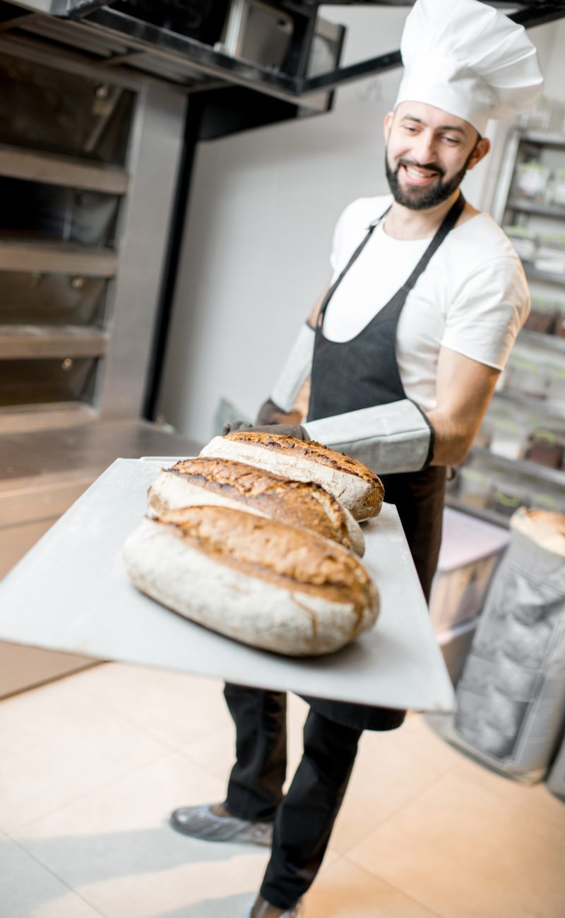 baker-with-baked-breads-at-the-bakery-E9EXTVT.jpg